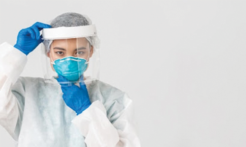 A Female Doctor Putting On A Face Shield Over A Mask