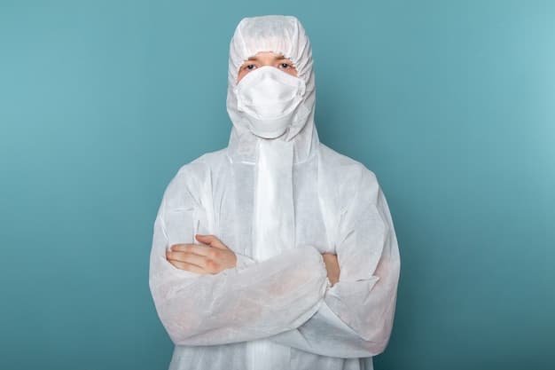 Front view of a young male in a white special suit wearing a sterile protective mask